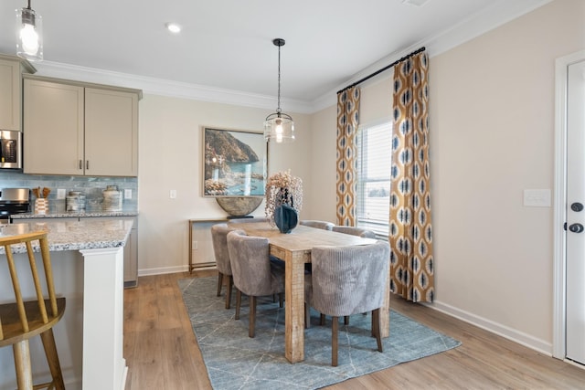 dining space with light wood-type flooring and ornamental molding