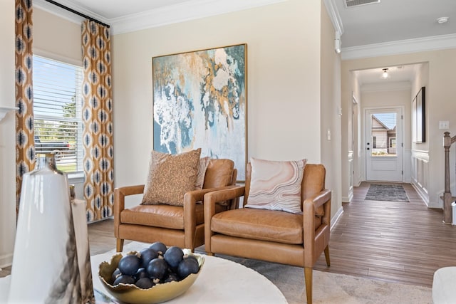 living room featuring wood-type flooring, plenty of natural light, and crown molding