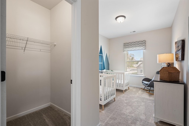 carpeted bedroom featuring a nursery area