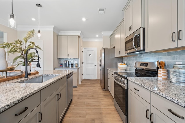 kitchen with appliances with stainless steel finishes, gray cabinetry, sink, pendant lighting, and light hardwood / wood-style floors