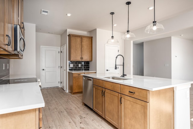 kitchen with appliances with stainless steel finishes, light wood-type flooring, a center island with sink, and sink