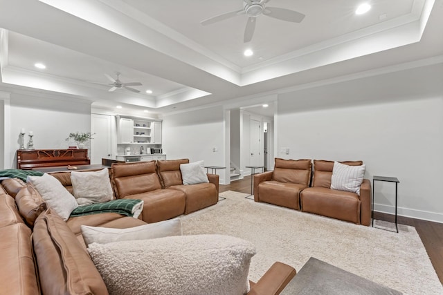 living room with crown molding, dark hardwood / wood-style floors, ceiling fan, and a tray ceiling