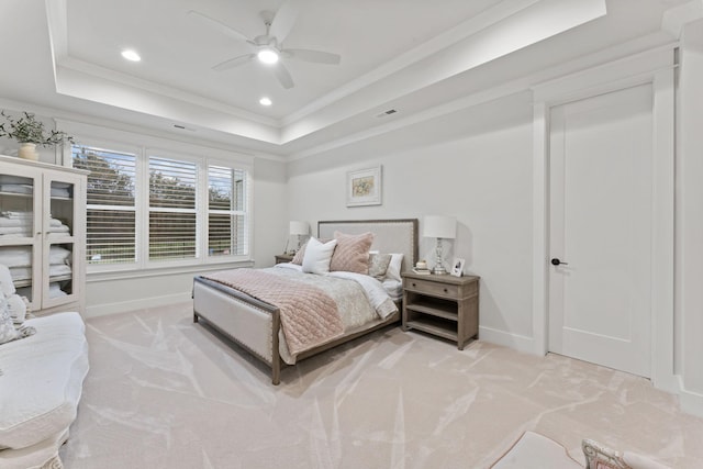 bedroom with ceiling fan, ornamental molding, a tray ceiling, and light carpet