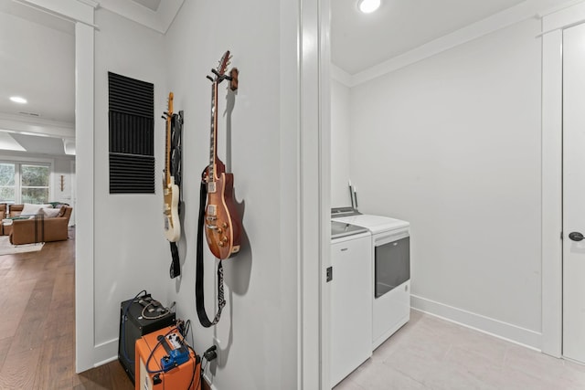 laundry room featuring light hardwood / wood-style flooring, ornamental molding, and washing machine and dryer