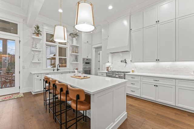 kitchen with white cabinetry, a kitchen bar, hanging light fixtures, a center island, and stainless steel appliances