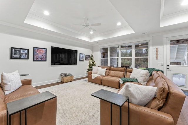 living room with hardwood / wood-style flooring, ceiling fan, ornamental molding, and a raised ceiling