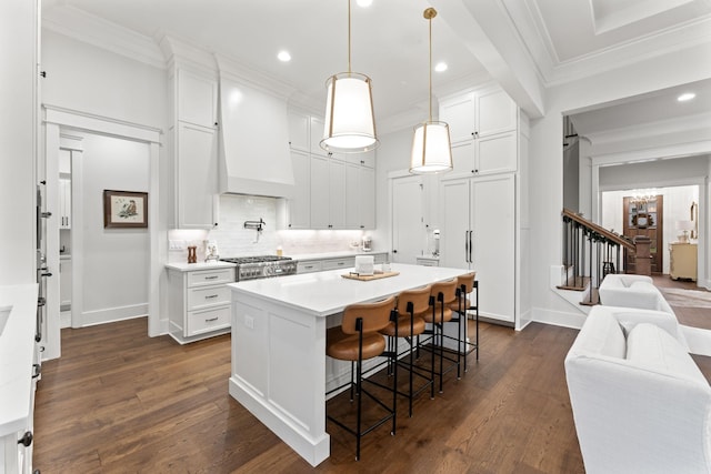 kitchen featuring premium range hood, decorative light fixtures, a center island, and white cabinets