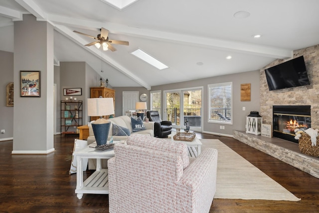 living room featuring ceiling fan, a stone fireplace, dark hardwood / wood-style flooring, and lofted ceiling with skylight