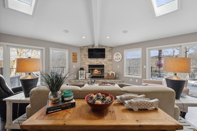 living room with a stone fireplace and lofted ceiling with skylight