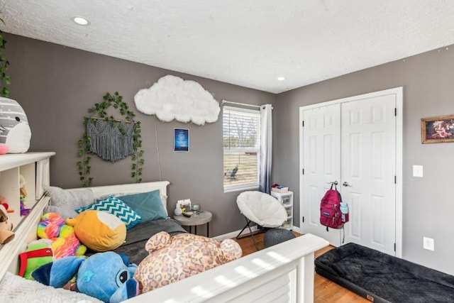 bedroom with hardwood / wood-style flooring, a textured ceiling, and a closet