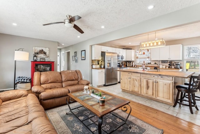 living room with a textured ceiling, light hardwood / wood-style flooring, and ceiling fan