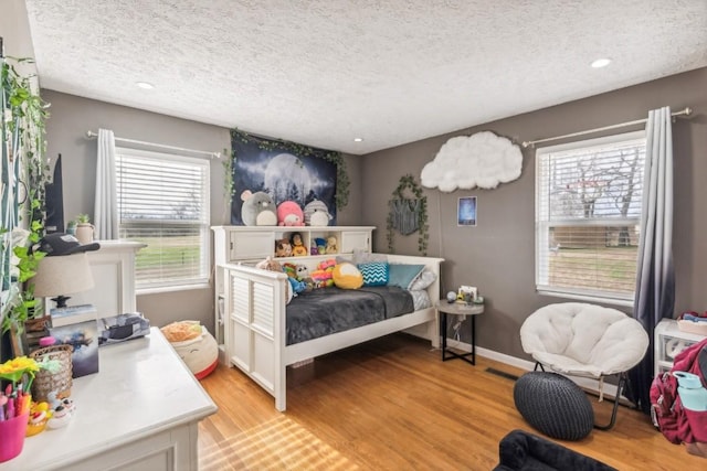 bedroom with a textured ceiling and light hardwood / wood-style floors