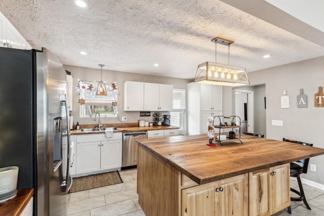 kitchen with wood counters, appliances with stainless steel finishes, a center island, and pendant lighting