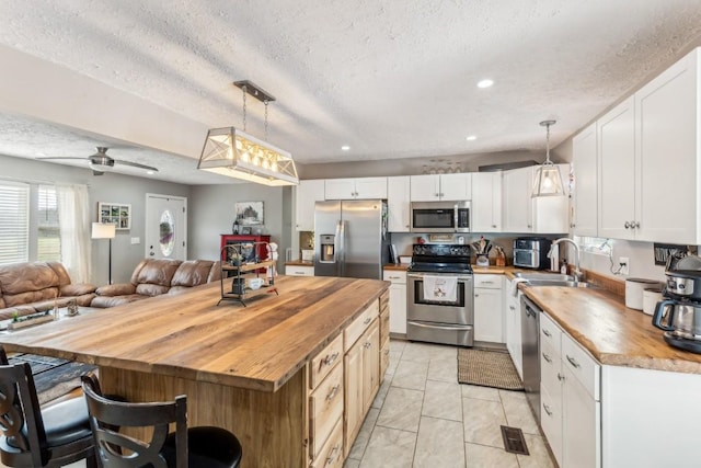 kitchen with wooden counters, decorative light fixtures, stainless steel appliances, and a kitchen island