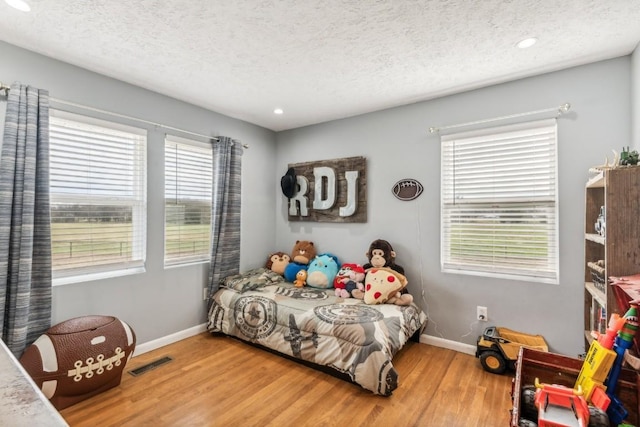 bedroom featuring multiple windows, a textured ceiling, and light wood-type flooring