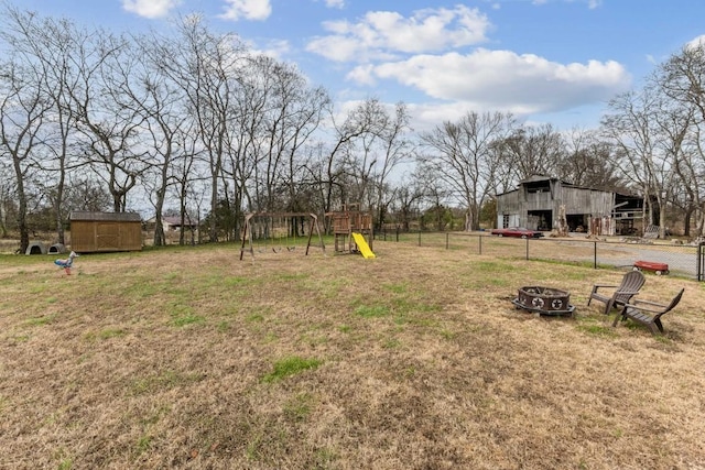 view of yard with an outbuilding, a playground, and an outdoor fire pit