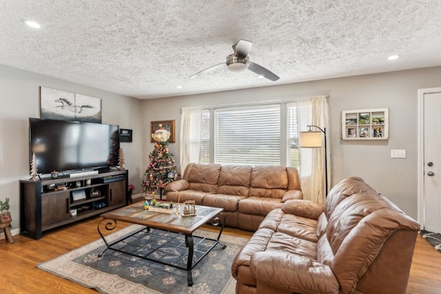 living room featuring a textured ceiling, light hardwood / wood-style floors, and ceiling fan