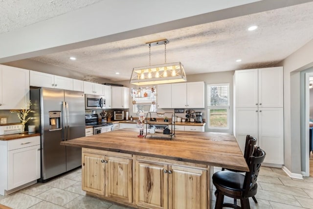 kitchen featuring butcher block countertops, white cabinets, and appliances with stainless steel finishes