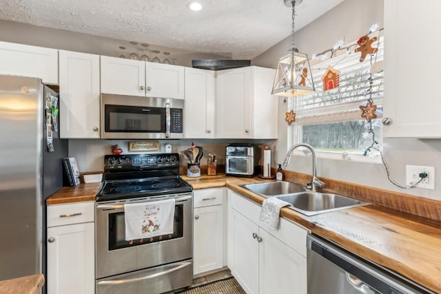 kitchen featuring white cabinets, hanging light fixtures, and appliances with stainless steel finishes