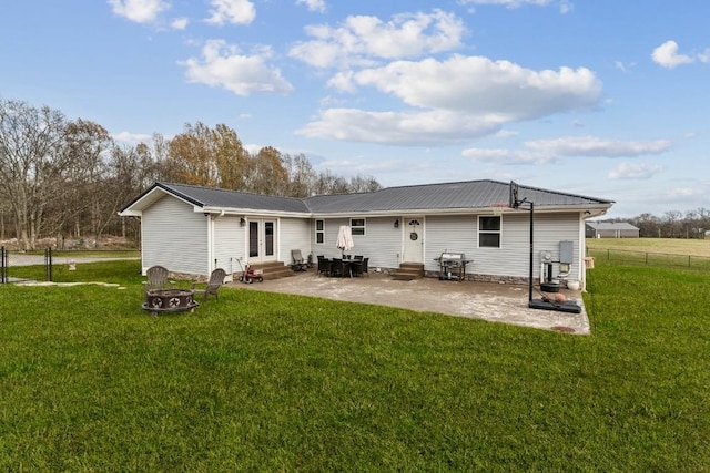 rear view of property featuring a lawn, a patio, an outdoor fire pit, and french doors