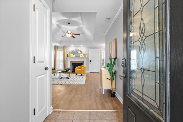 entryway featuring light hardwood / wood-style floors, a raised ceiling, ceiling fan, and crown molding