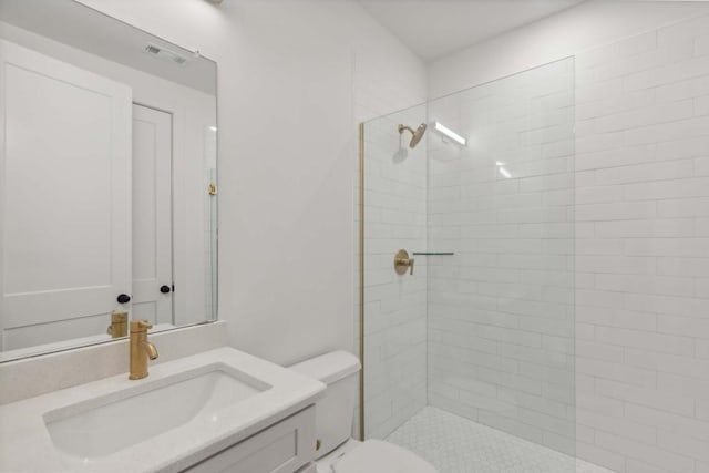 bathroom with a tile shower, vanity, and toilet