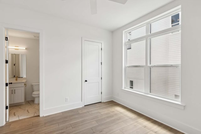 unfurnished bedroom with connected bathroom, ceiling fan, sink, light hardwood / wood-style floors, and a closet