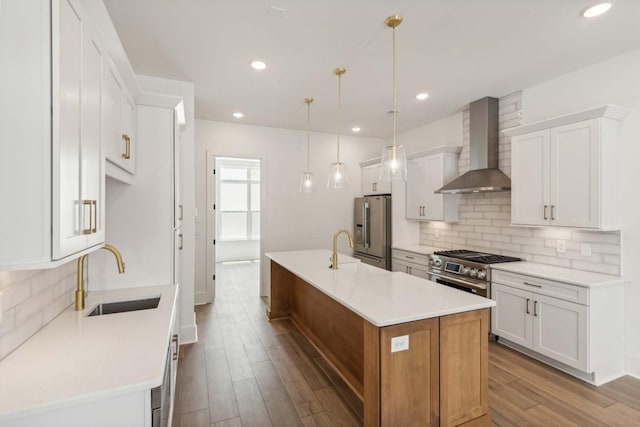 kitchen with pendant lighting, white cabinetry, wall chimney range hood, and sink