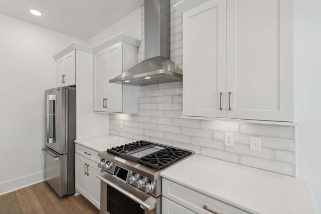 kitchen with white cabinetry, wall chimney exhaust hood, high quality appliances, decorative backsplash, and light wood-type flooring