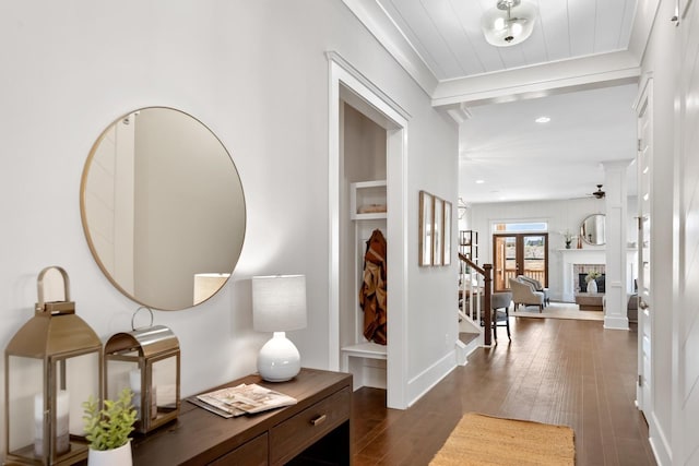 entrance foyer featuring ceiling fan, dark hardwood / wood-style flooring, crown molding, and a brick fireplace