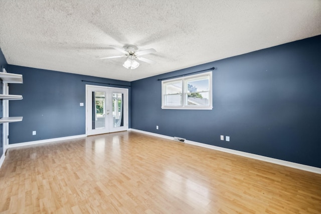 empty room featuring ceiling fan, light wood-type flooring, a textured ceiling, and french doors