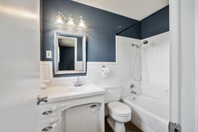 full bathroom with a textured ceiling, vanity, tiled shower / bath combo, tile walls, and toilet