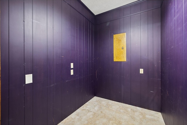 interior space with a textured ceiling and wood walls