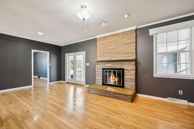 unfurnished living room with a fireplace, a textured ceiling, light hardwood / wood-style floors, and crown molding