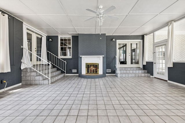 unfurnished living room featuring french doors, a paneled ceiling, and ceiling fan