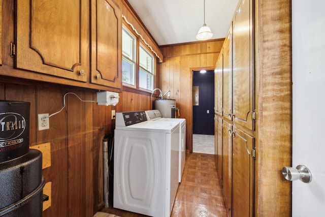 laundry room with washing machine and clothes dryer, parquet floors, cabinets, water heater, and wooden walls