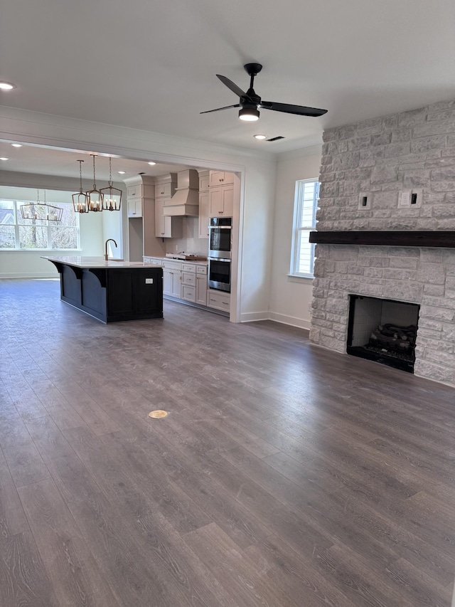 kitchen featuring premium range hood, dark wood finished floors, open floor plan, double oven, and a sink