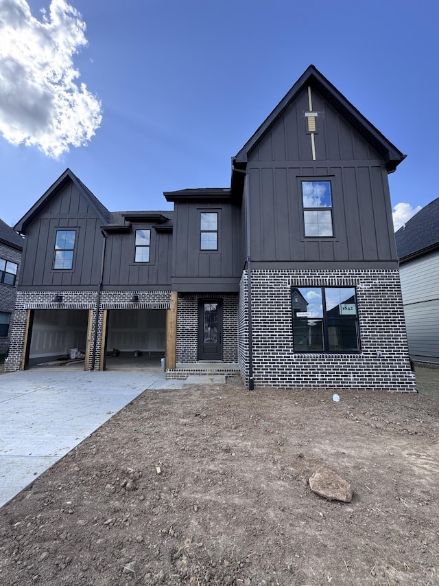 view of front of property with concrete driveway, brick siding, and board and batten siding