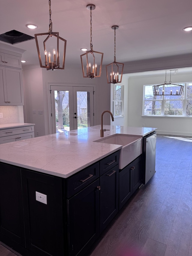 kitchen featuring a sink, dark wood-style flooring, french doors, stainless steel dishwasher, and a kitchen island with sink