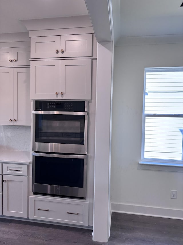 kitchen featuring double oven, a healthy amount of sunlight, and dark wood-style flooring