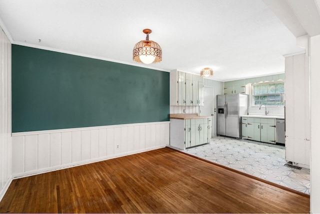 kitchen featuring stainless steel appliances, sink, decorative light fixtures, light wood-type flooring, and crown molding