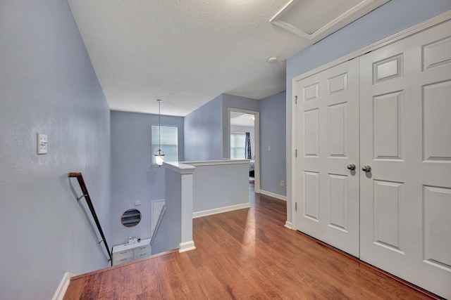 hall featuring wood-type flooring and a textured ceiling