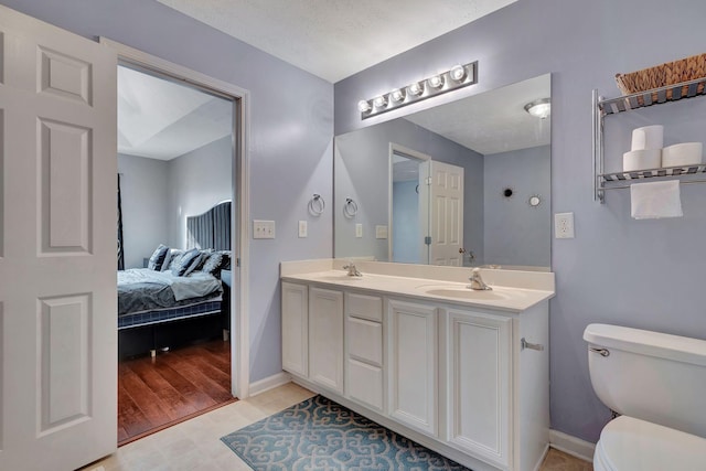 bathroom with hardwood / wood-style floors, vanity, toilet, and a textured ceiling