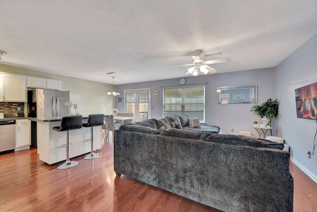 living room featuring a textured ceiling, ceiling fan with notable chandelier, and hardwood / wood-style flooring