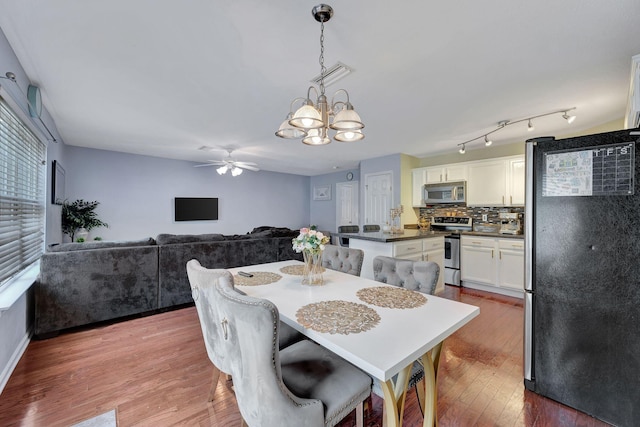 dining room featuring ceiling fan with notable chandelier and light hardwood / wood-style floors