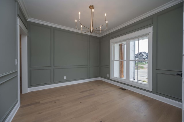 unfurnished dining area with light hardwood / wood-style floors, ornamental molding, and a notable chandelier