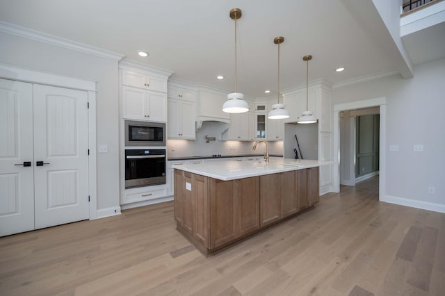 kitchen with white cabinetry, a large island, stainless steel appliances, light hardwood / wood-style flooring, and crown molding