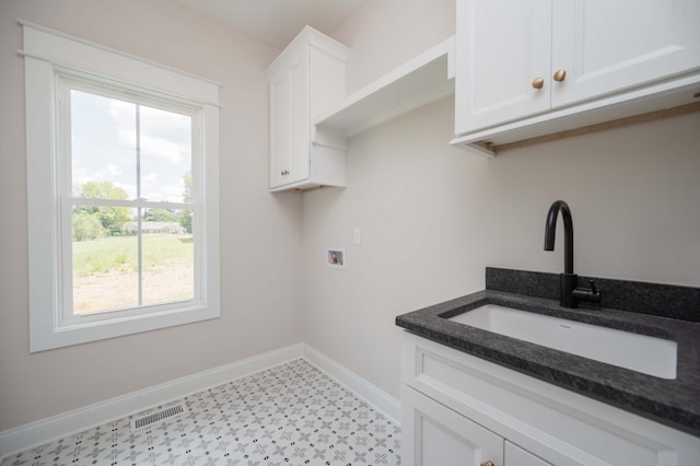 clothes washing area featuring cabinets, sink, and washer hookup