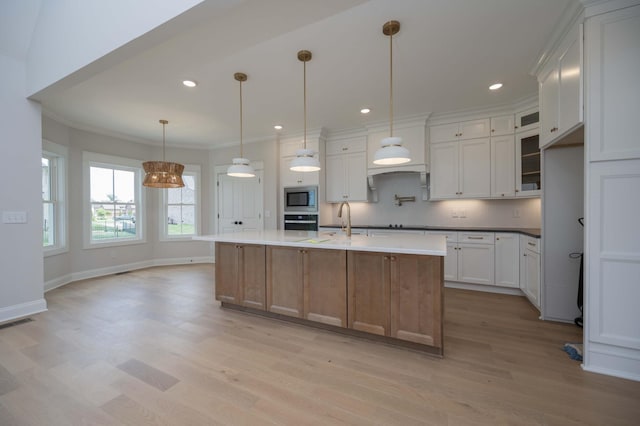 kitchen with appliances with stainless steel finishes, a center island with sink, and white cabinetry