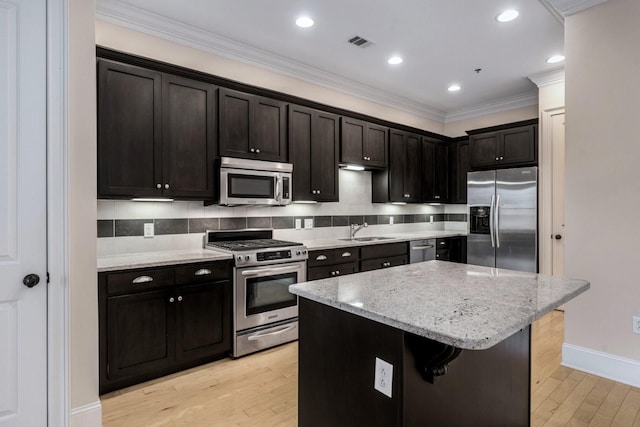 kitchen with sink, a center island, light stone countertops, and appliances with stainless steel finishes